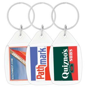 A hand holds a clear tear drop acrylic keychain featuring the Australian flag. The keychain has a silver ring and a logo.