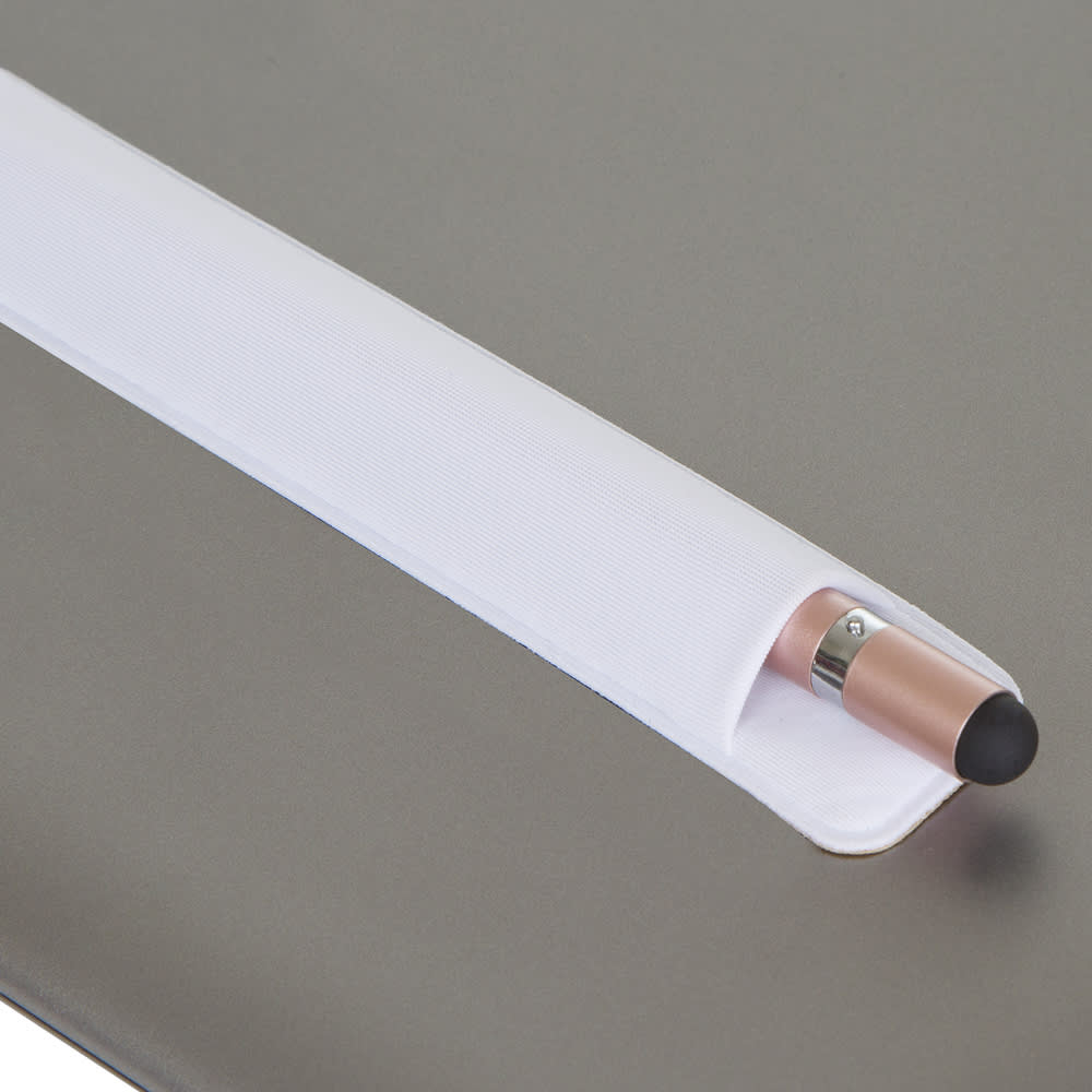 A metal pen with a rose gold finish and a black tip, resting in a white holder on a grey surface.