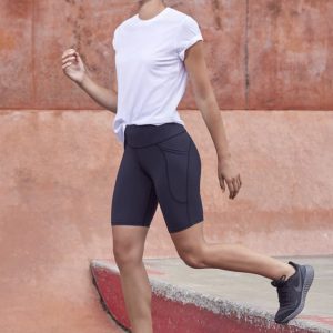 A model wearing black women's Luna bike shorts paired with a white t-shirt and black athletic shoes.