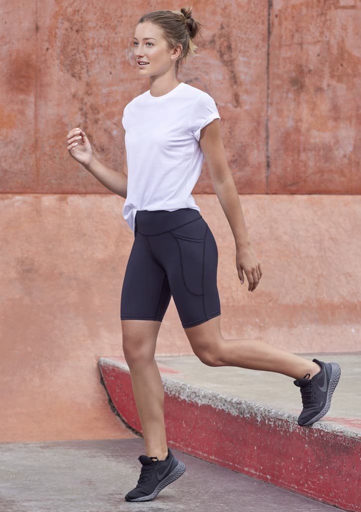 A model wearing black women's Luna bike shorts paired with a white t-shirt and black athletic shoes.