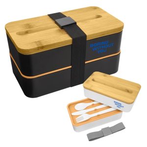 A bamboo and black lunch box pack with cutlery and a strap, featuring a logo on the lid.
