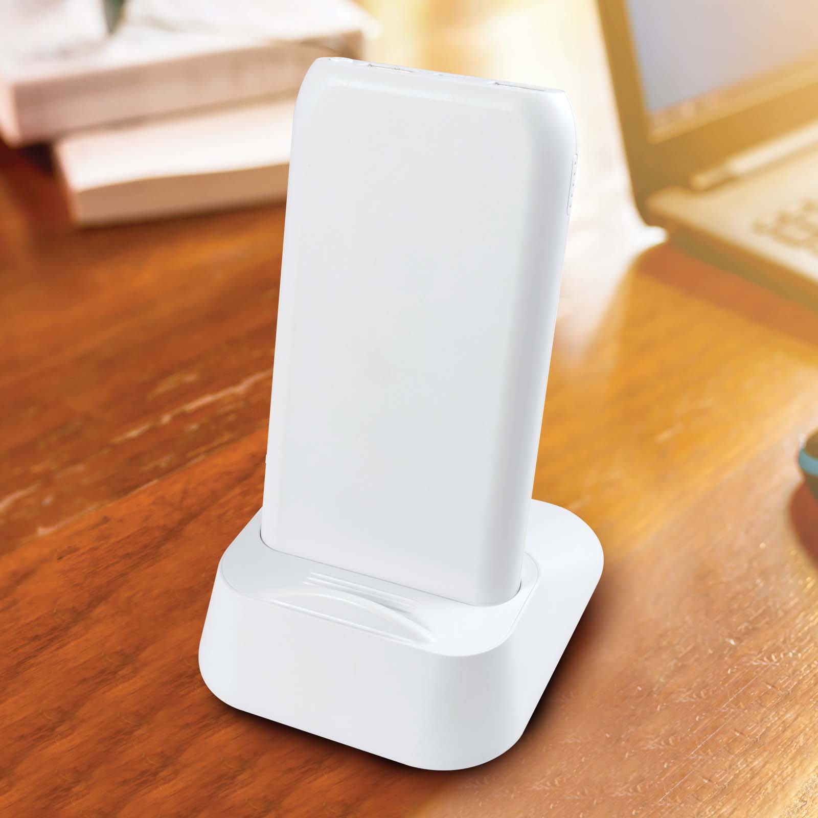 A wireless power bank sits in a charging station, featuring a sleek white design ideal for modern technology.