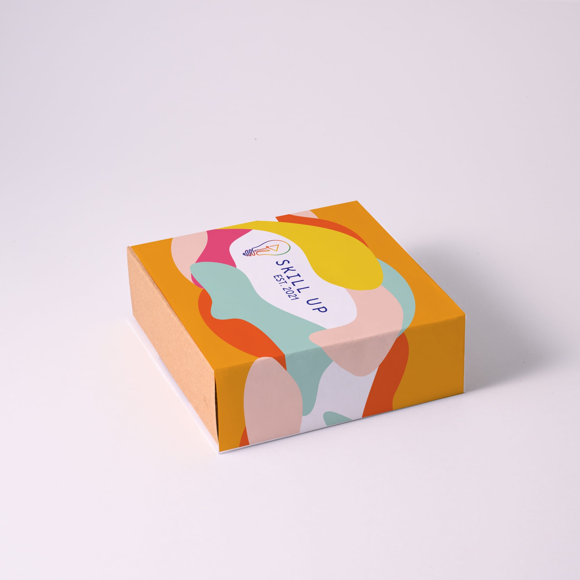 A colorful box with abstract shapes and a logo on top, featuring shades of yellow, orange, pink, and green.