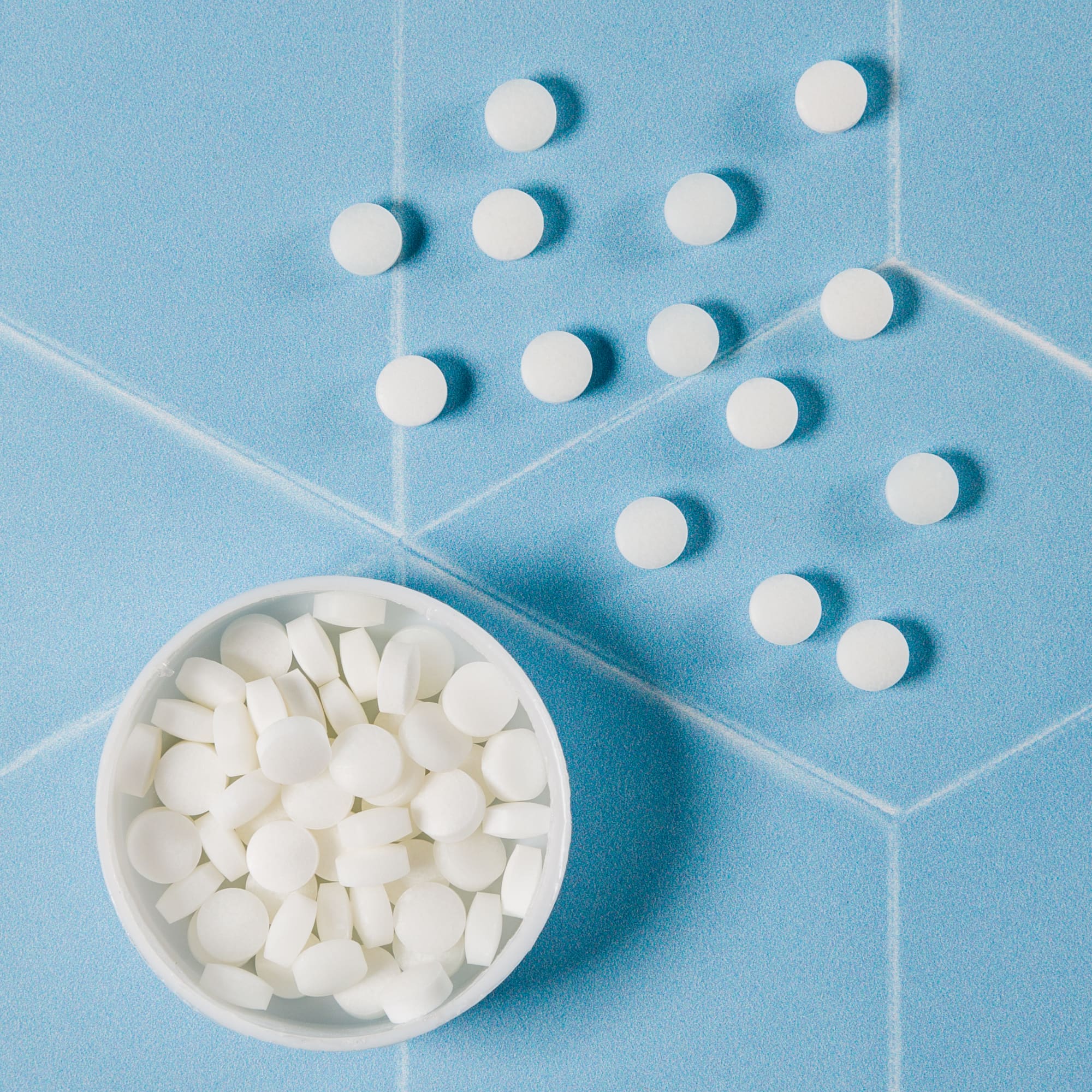 A round, white mint tin with a distinctively shaped lid. The surface is smooth and glossy, suitable for packaging mints.