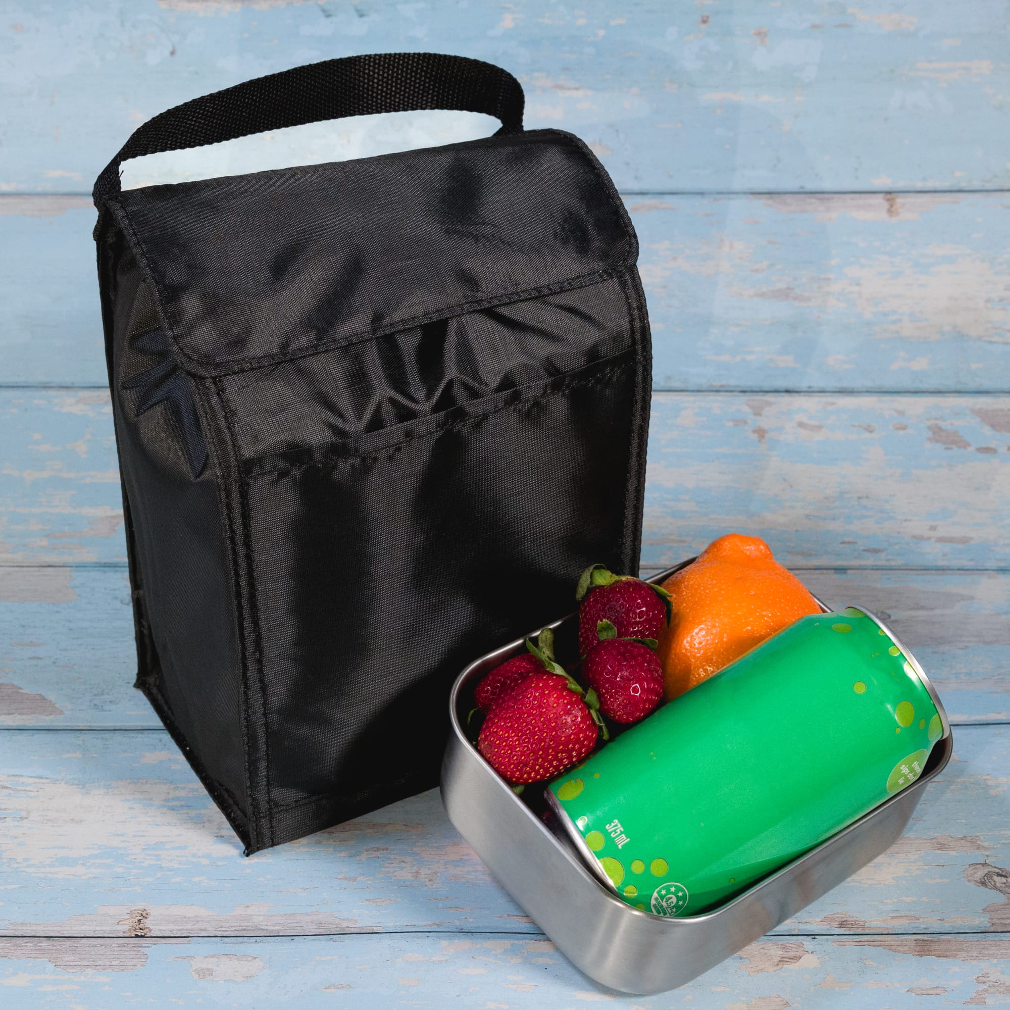 A black cooler lunch bag with a drink can, an orange, and strawberries inside a metal container.