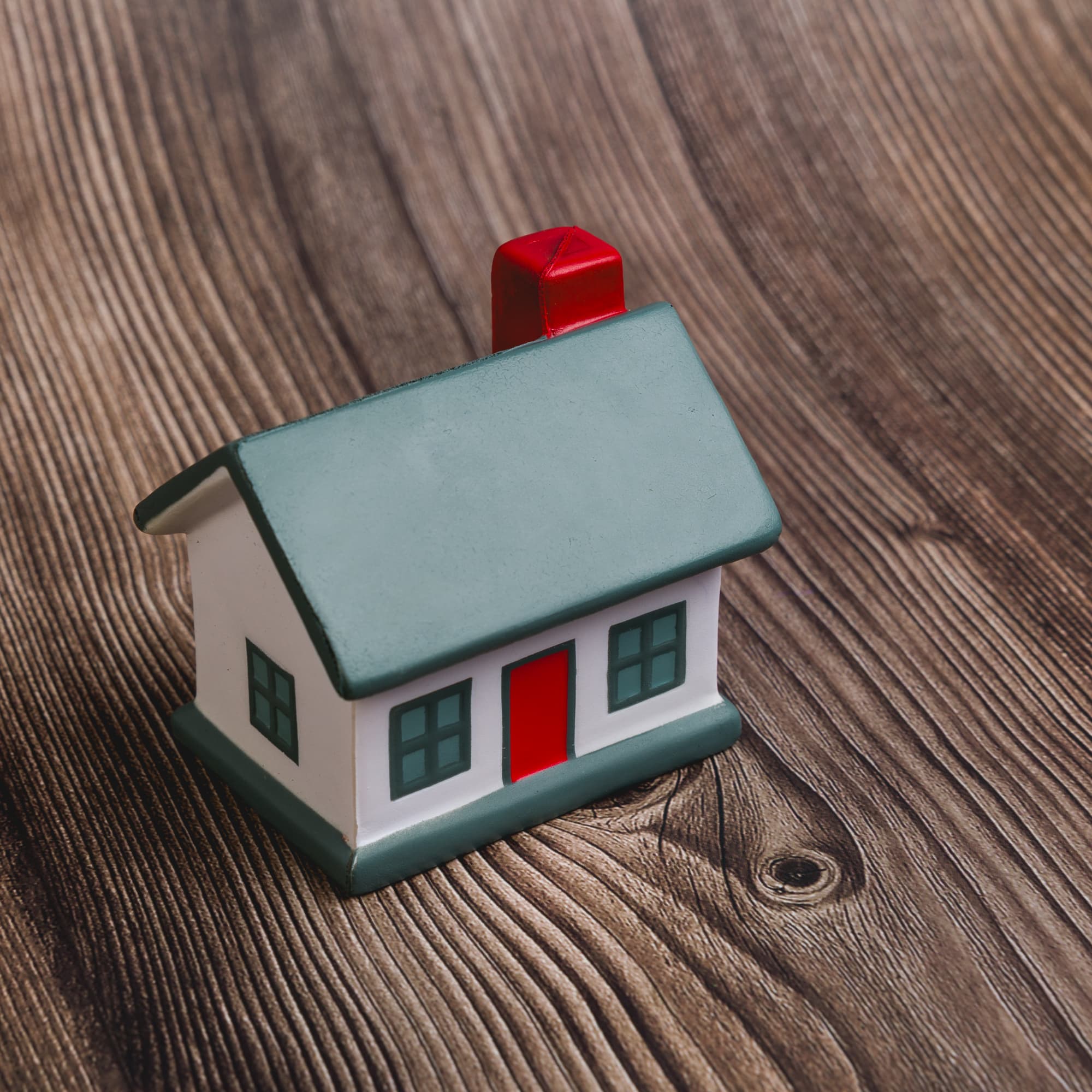 A small house-shaped stress reliever in green, white, and red colors, featuring a chimney and windows.