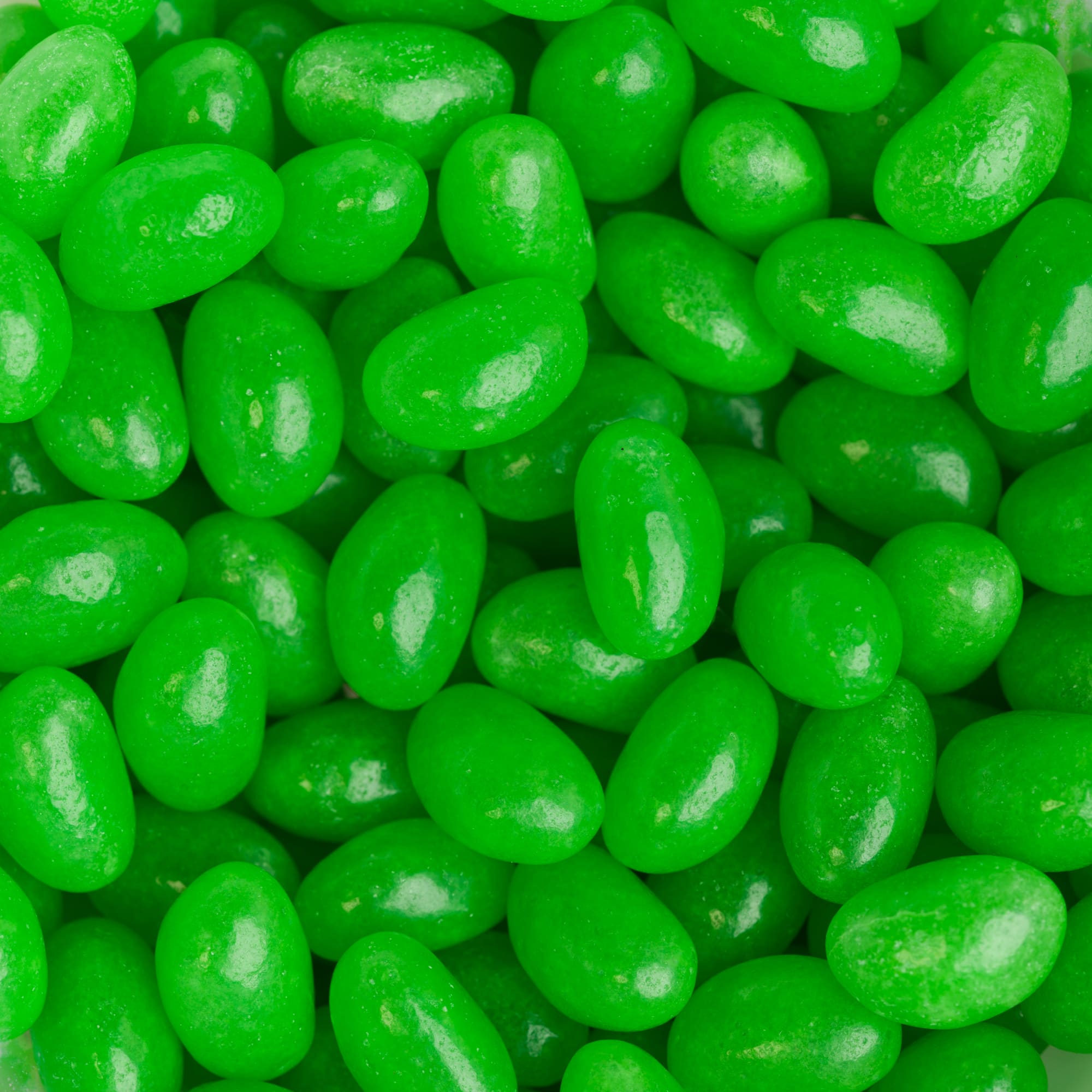 Bright green mini jelly beans in a close-up view, showcasing their shiny, smooth texture.
