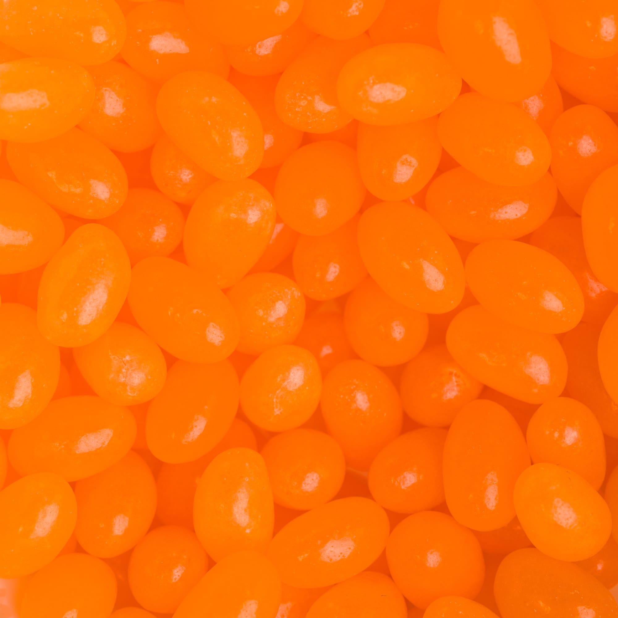 Mini jelly beans in a vibrant orange color, ideal for promotional or confectionery use.