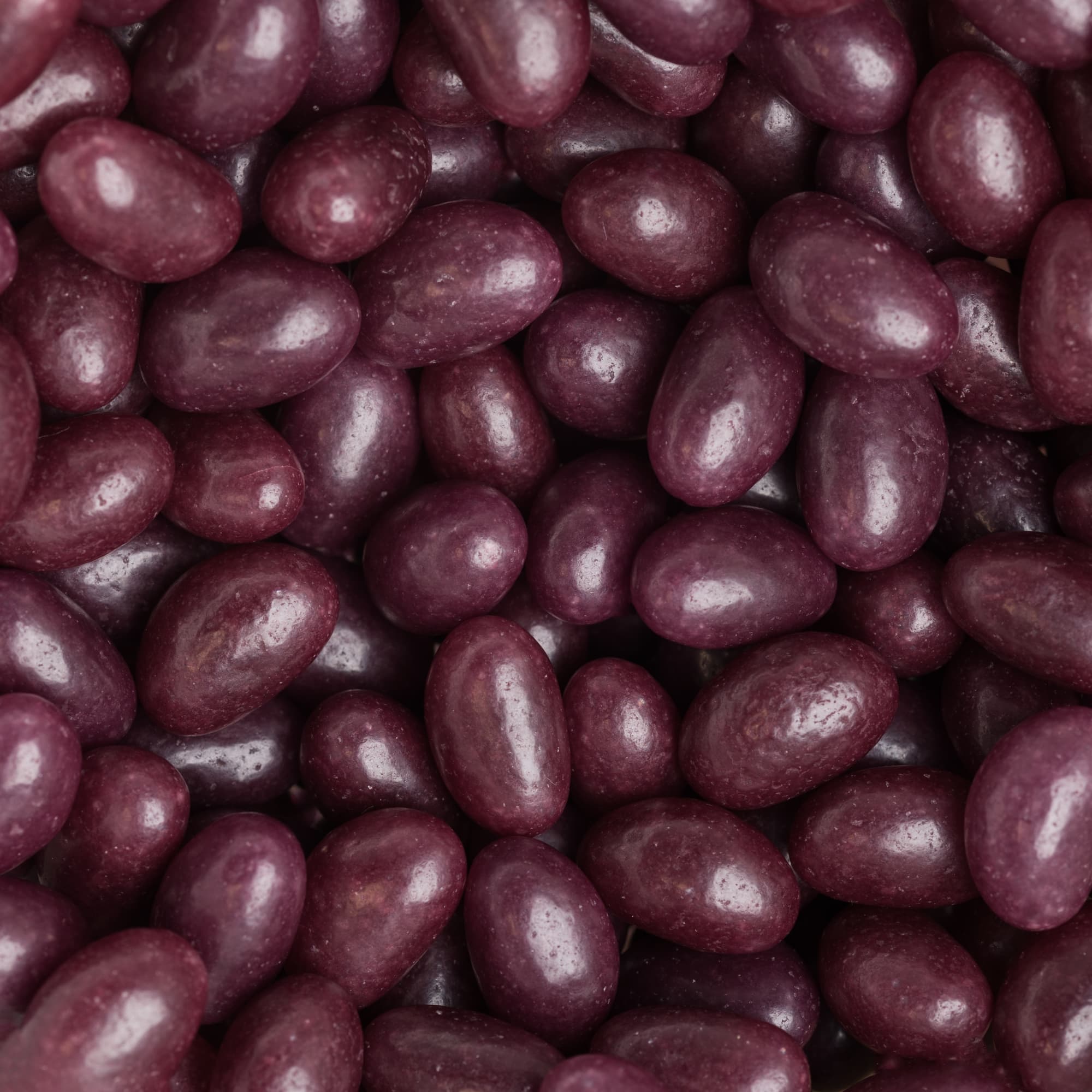 A close-up of purple jelly beans, showcasing their glossy texture and various shapes.