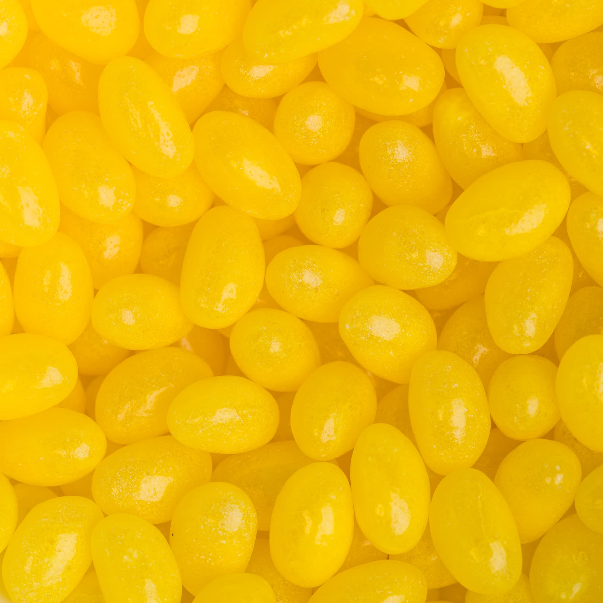 Mini jelly beans in a bright yellow color, showcasing a shiny, smooth surface.