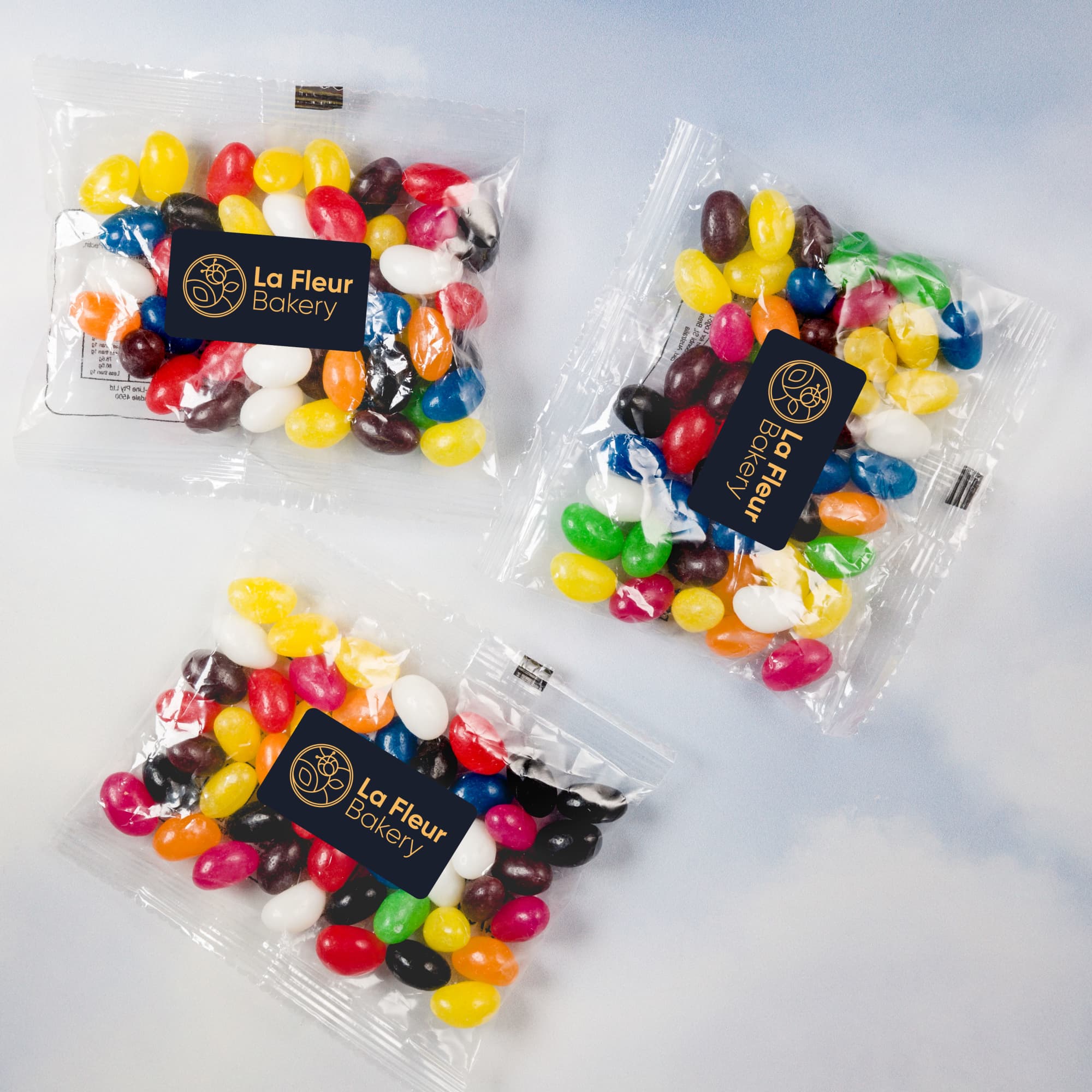 Assorted colourful mini jelly beans in three 50 gram cello bags, each featuring the La Fleur Bakery logo.