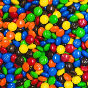 A colorful assortment of M&M's in vibrant hues including red, blue, green, yellow, orange, and black.