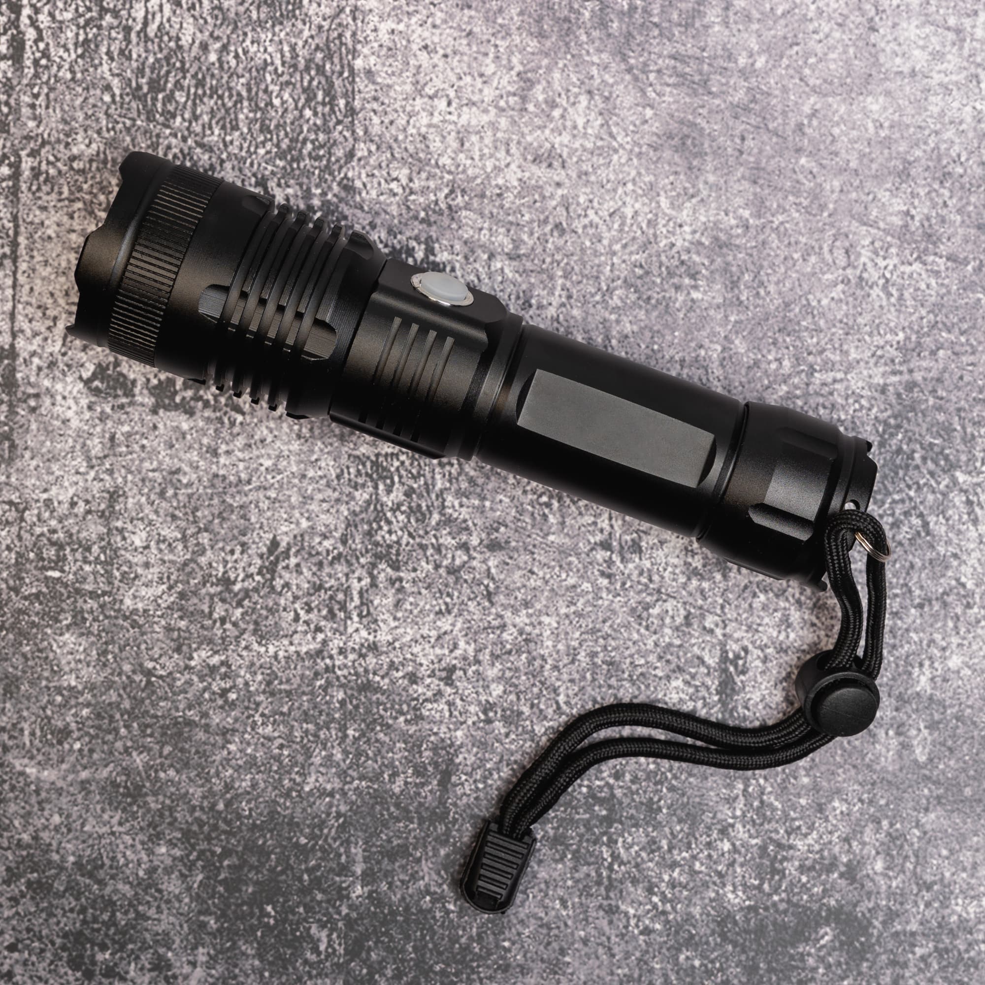 A rechargeable torch in sleek black design with a textured grip and a wrist strap.