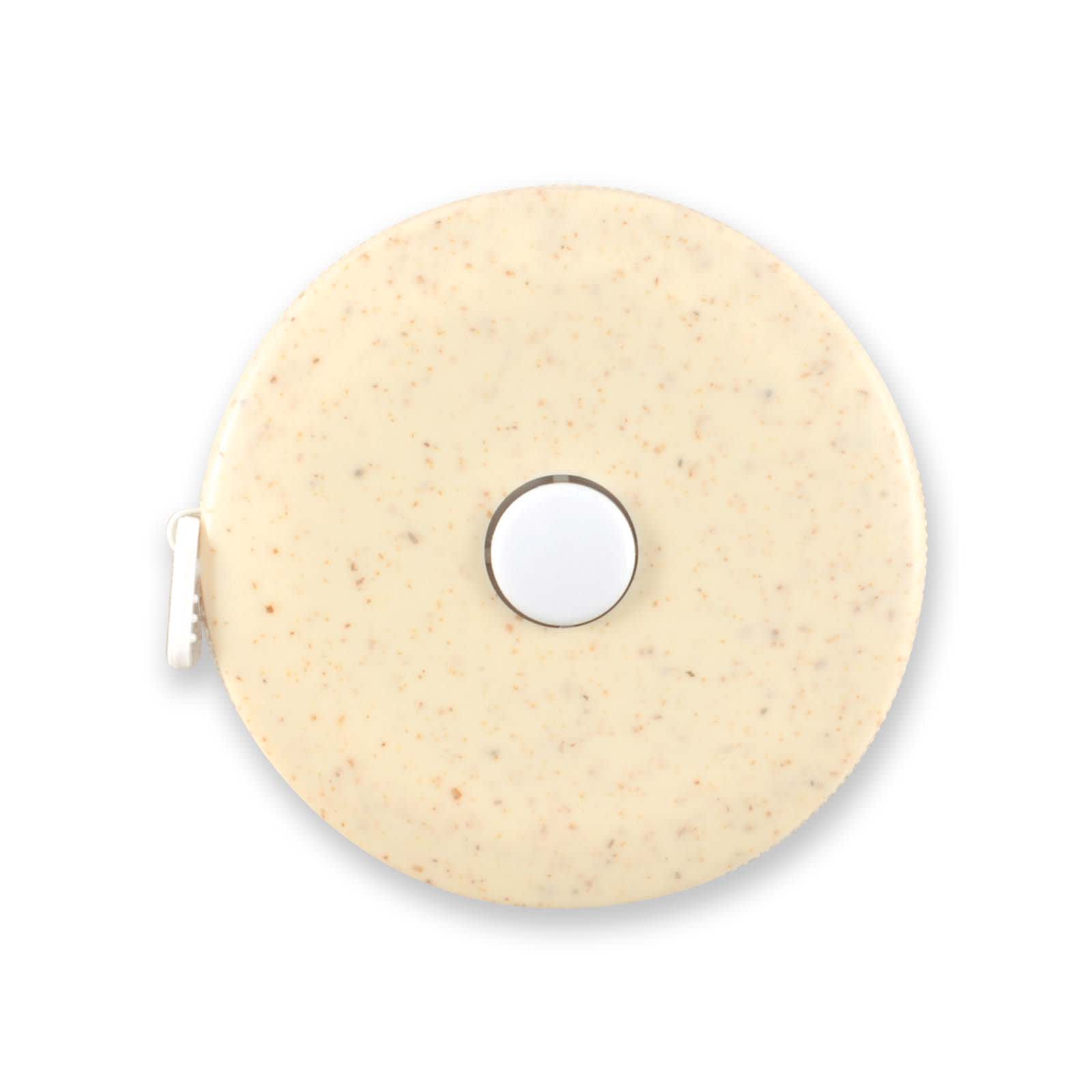 A tape measure featuring a circular body made of wheat fiber, showcasing a smooth, light-colored surface with speckles.