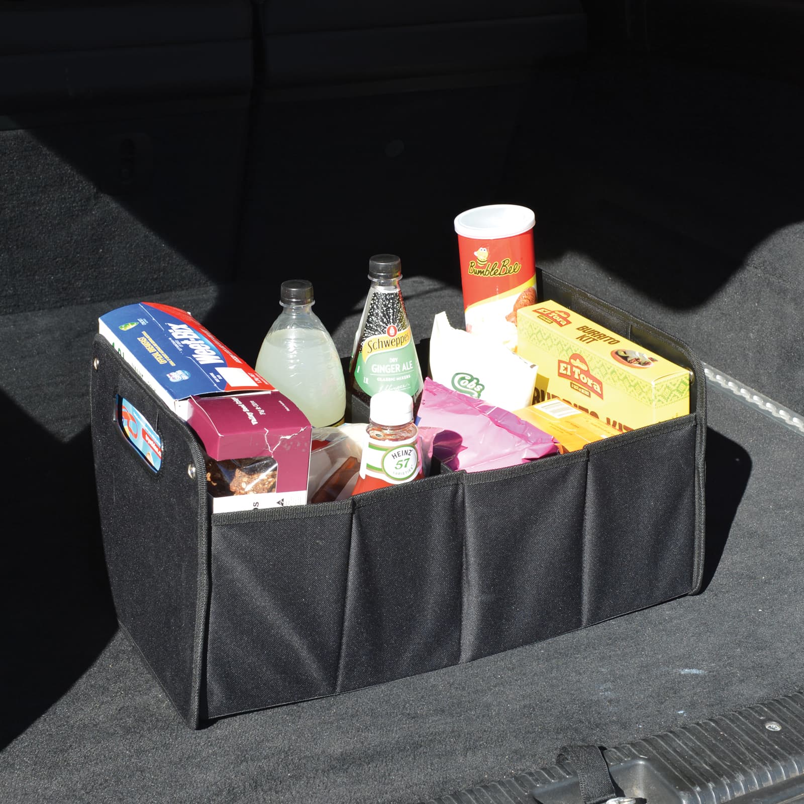 A black cargo storage organizer filled with various drinks and snacks, set against a dark background.