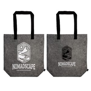 A grey tote bag with black handles, displayed by a person holding it by the straps. The bag has a logo.
