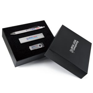 A gift set featuring a silver pen, metal USB drive, and a metal card holder in a sleek black box with branding.