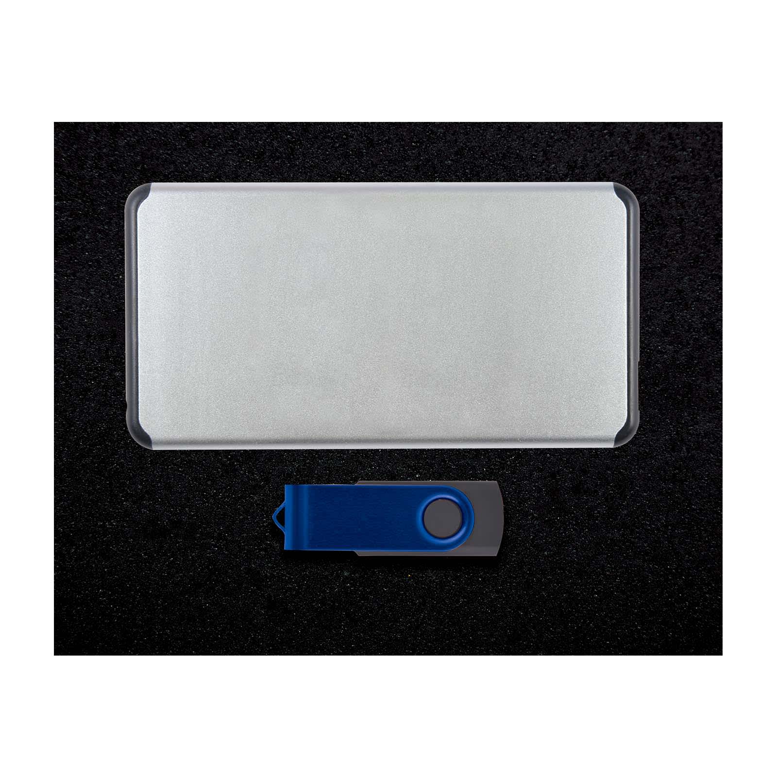 A silver power bank and a blue USB flash drive arranged on a dark surface, featuring a logo on the flash drive.