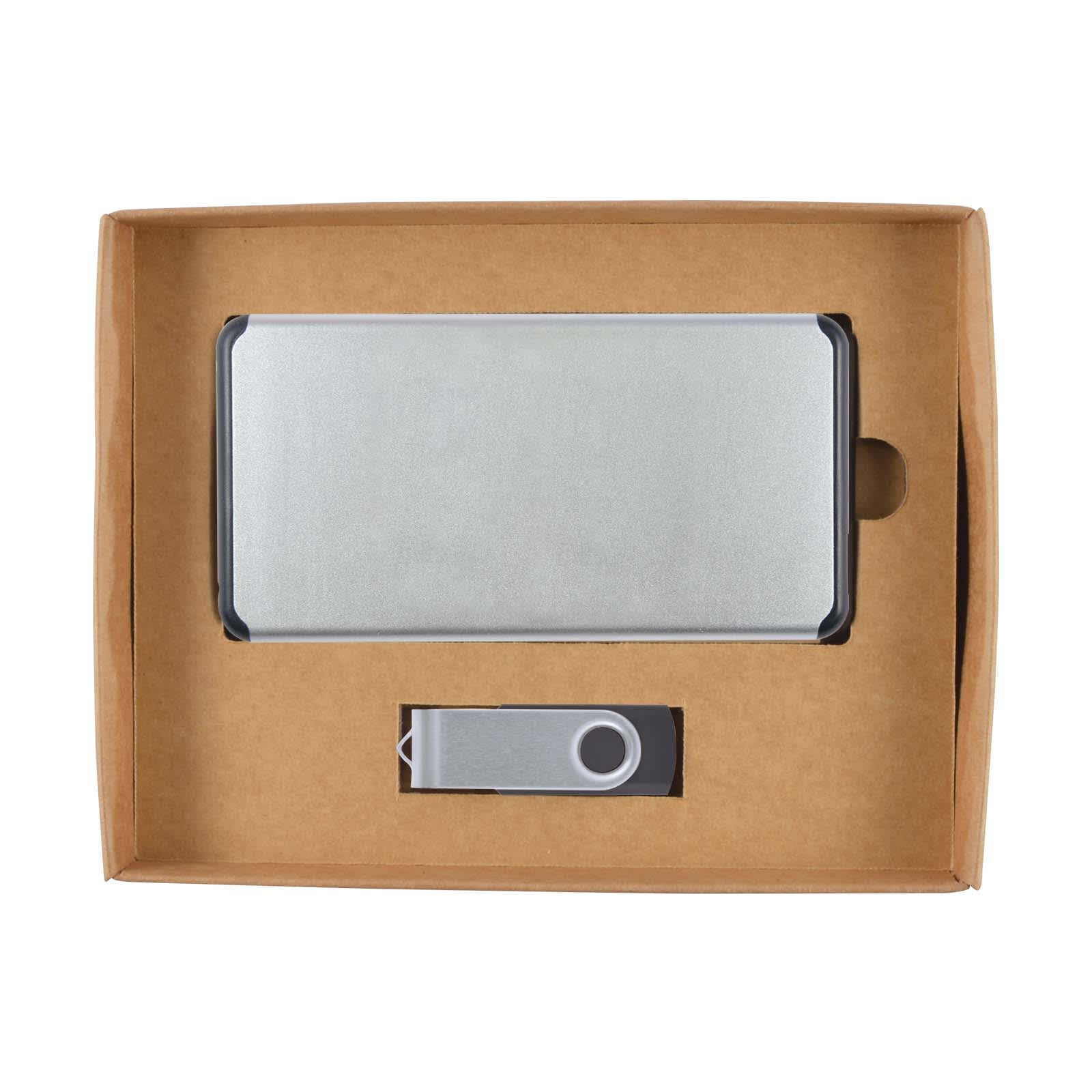 A silver power bank and matching USB drive are presented in a cardboard gift box. The box has a simple design.