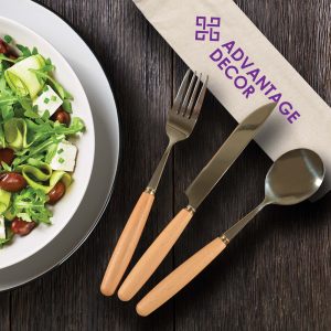 A cutlery set with a fork, knife, and spoon featuring wooden handles, placed beside a salad in a bowl.