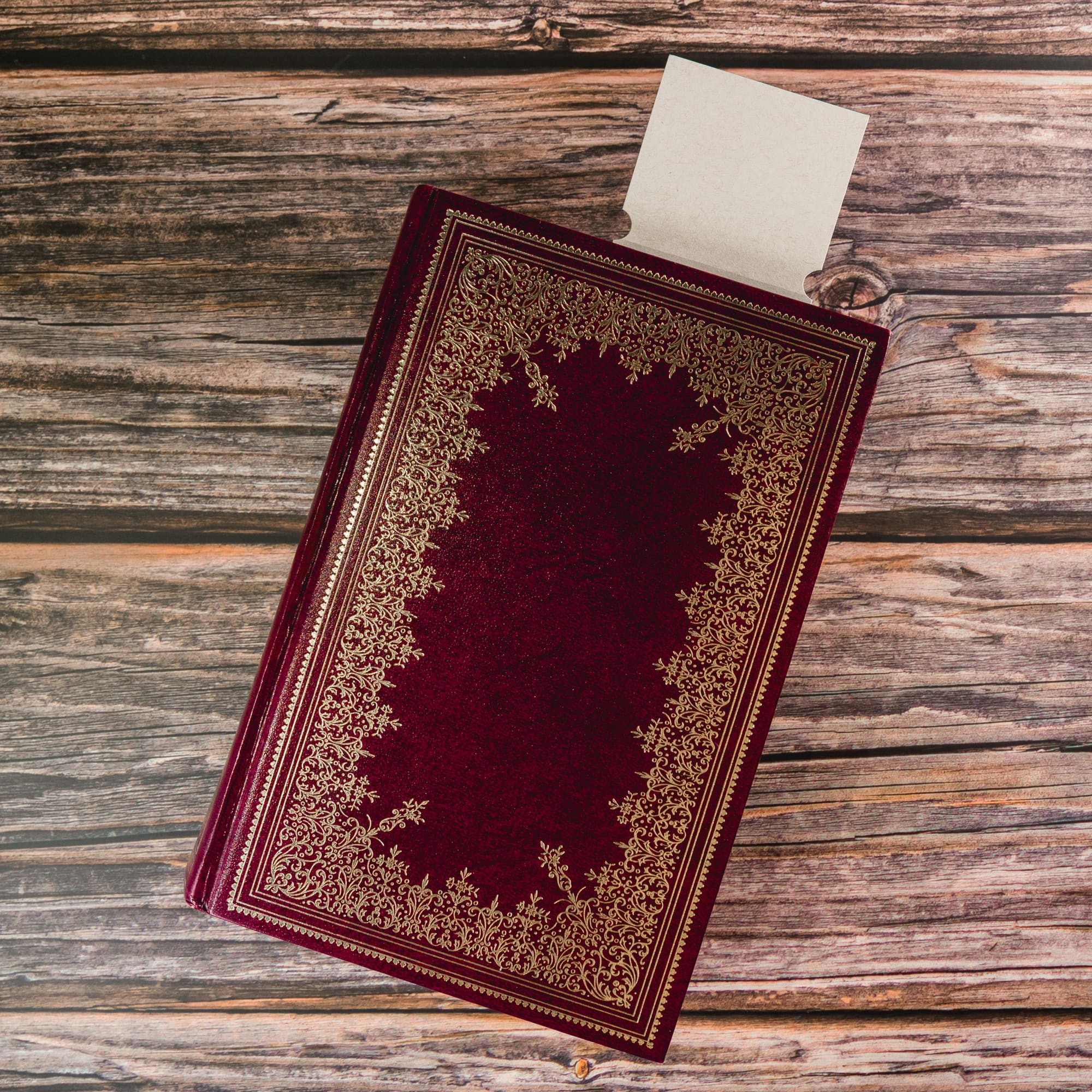 A rectangular bookmark resembling a milk carton sits atop a decorative book with gold embellishments.