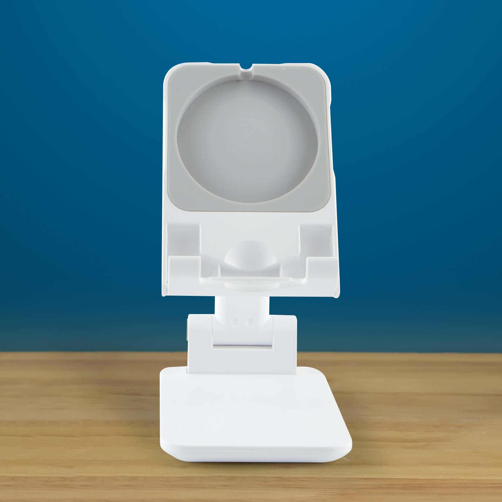A white phone stand with an adjustable holder and a square base on a wooden surface, against a blue background.