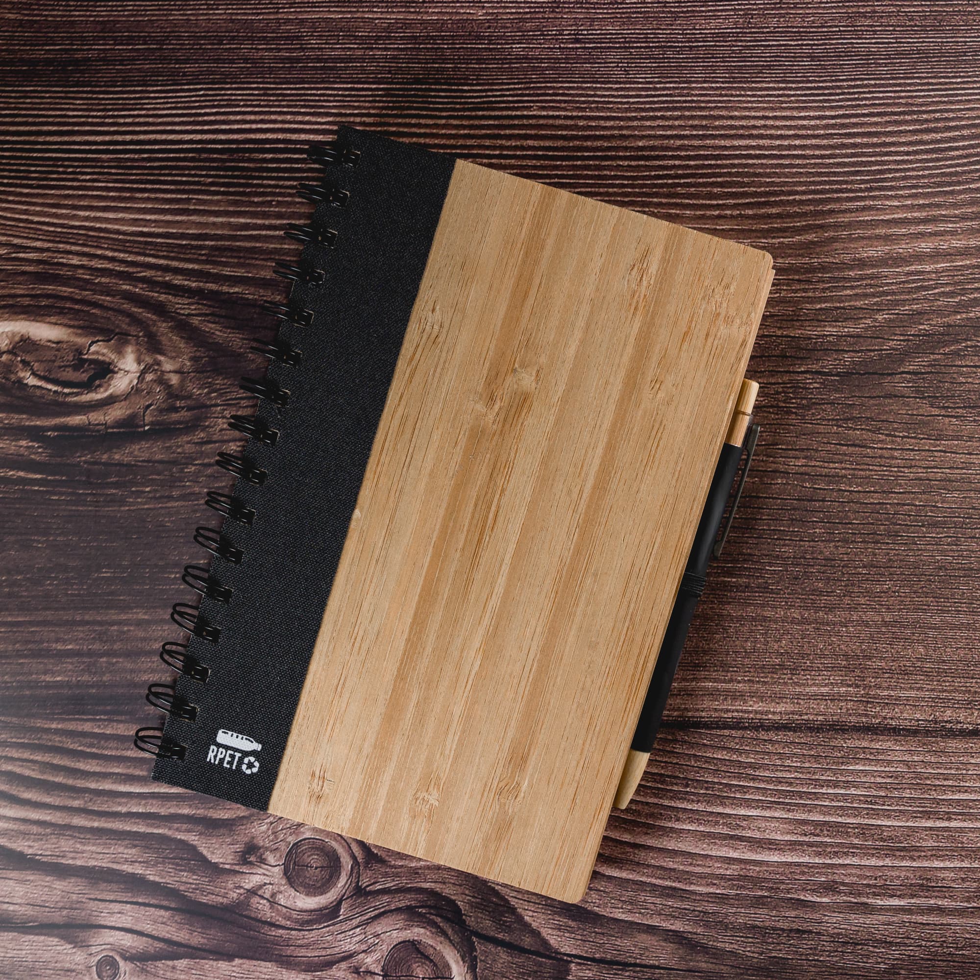 A bamboo and black A5 spiral notebook featuring a sturdy cover and a pen attached.