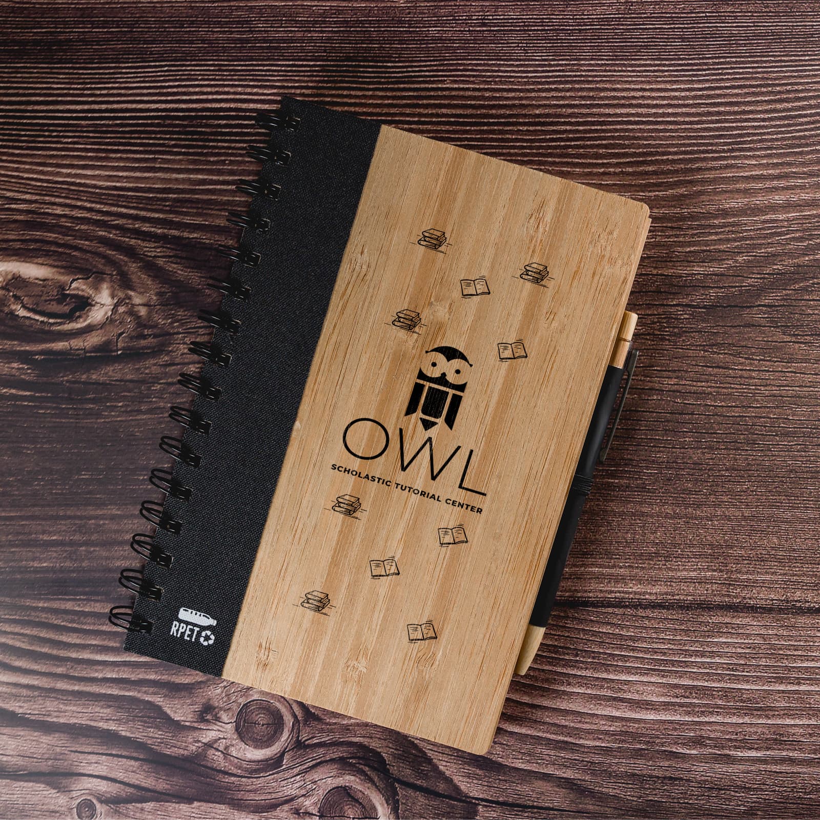 A brown and black spiral notebook with a textured cover, featuring a logo and a pen beside it.