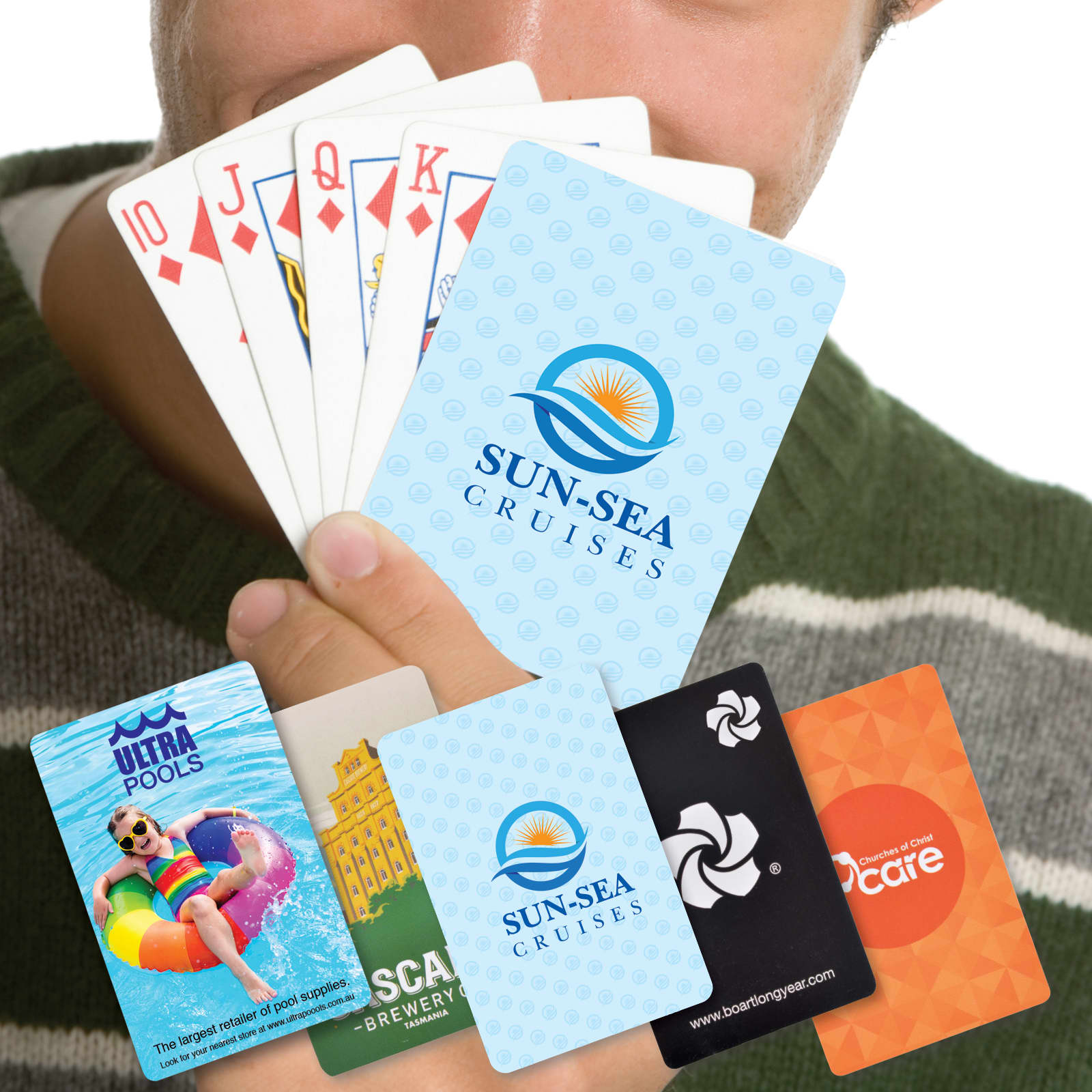 A person holding a fan of playing cards featuring various designs and colors, including logos and promotional cards.