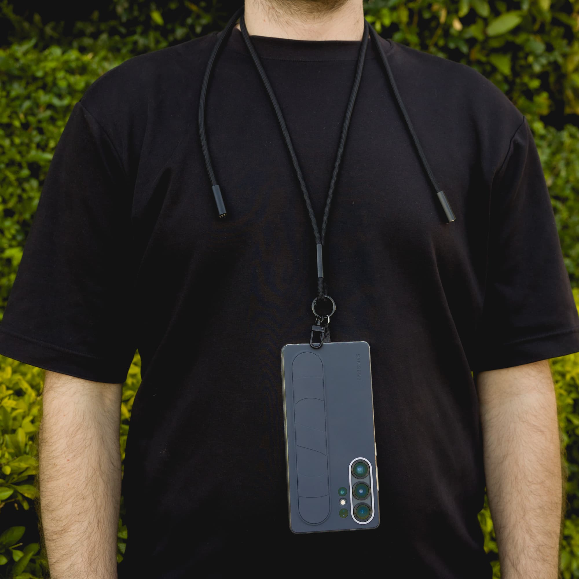 A black phone lanyard is worn around the neck, holding a smartphone securely attached.