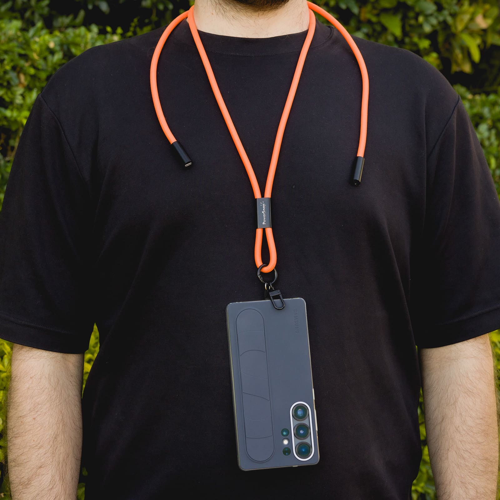 An orange phone lanyard is worn around the neck, holding a smartphone. The lanyard has a sleek design with attachments.