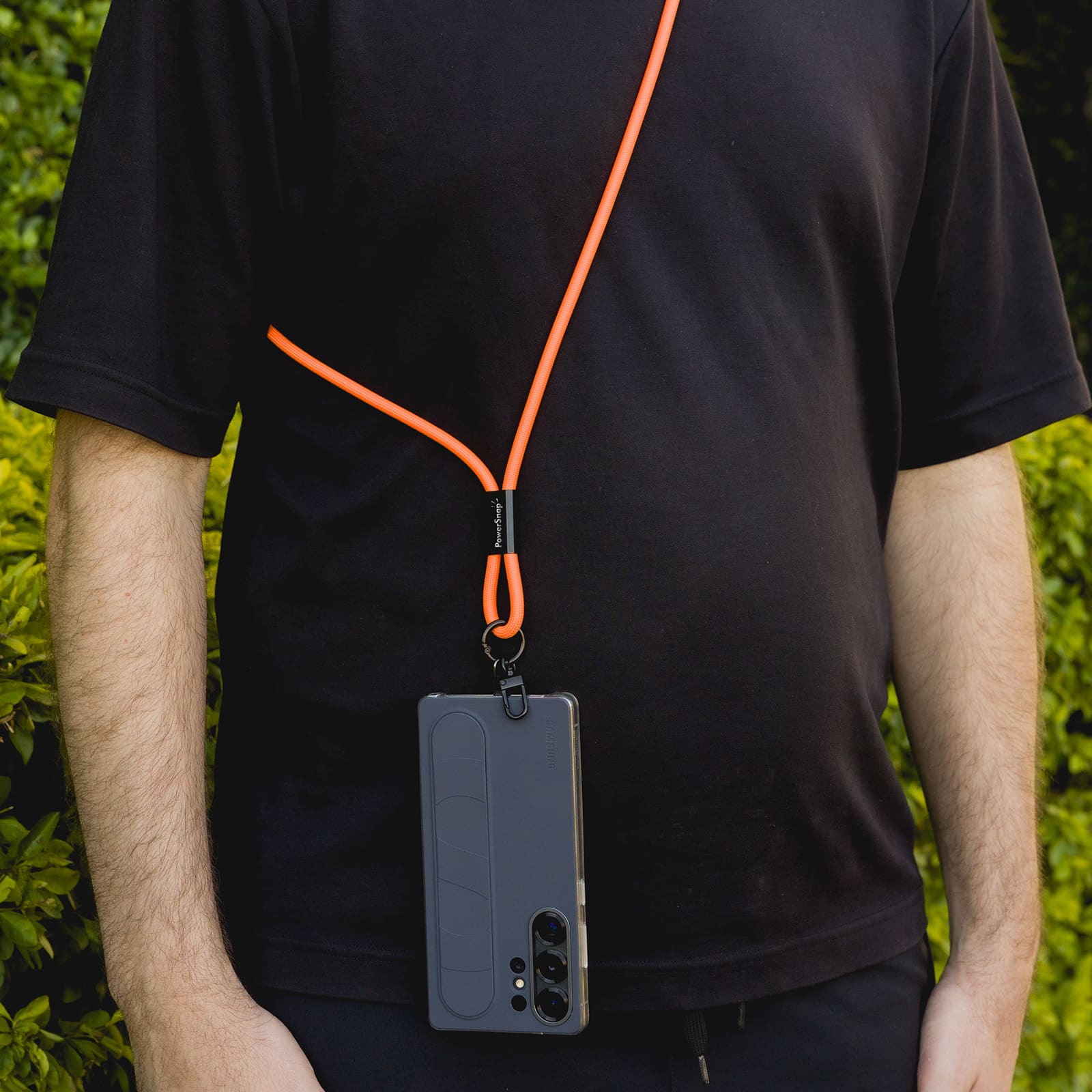 A phone lanyard with an orange cord is worn around the neck, holding a black smartphone.