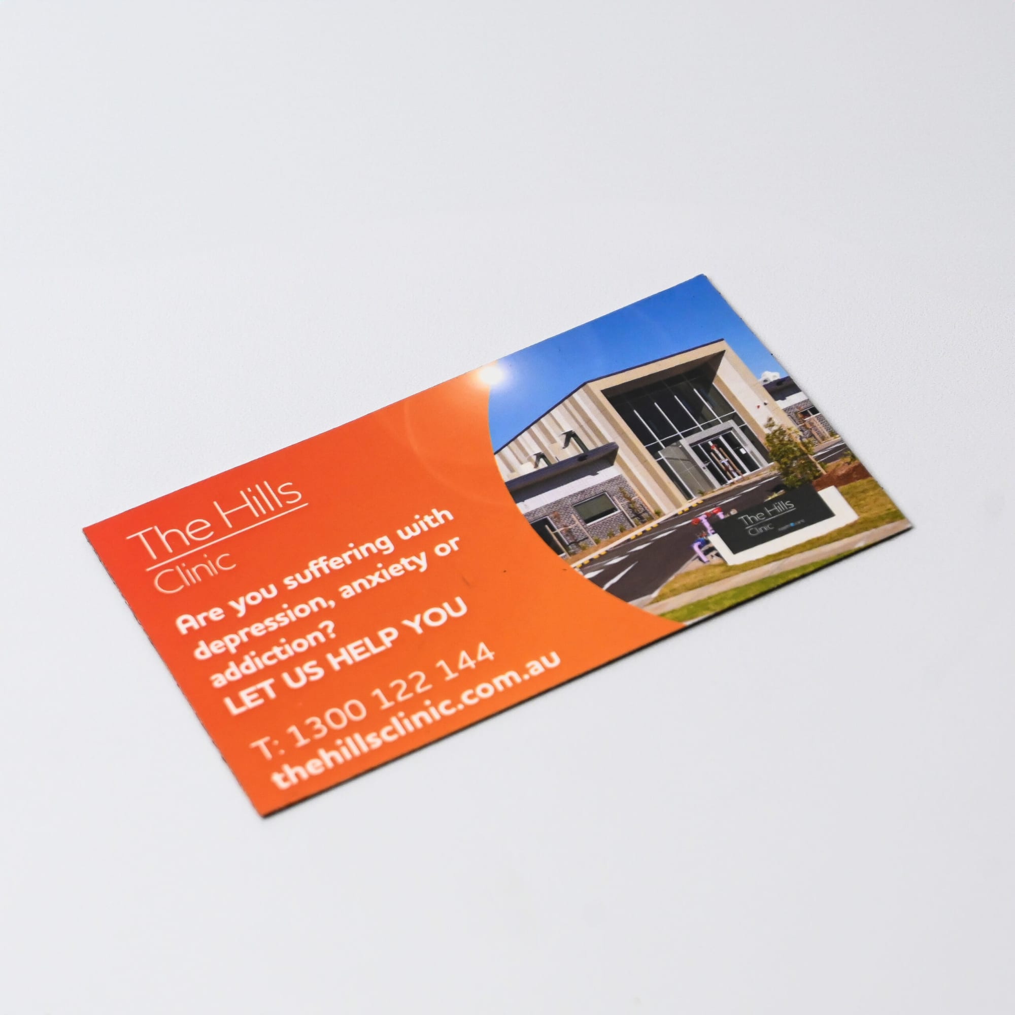 A rounded-corner fridge magnet featuring a vibrant design with an image of a building and a logo.