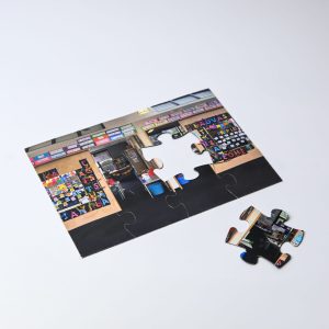 A5 Magnetic Jigsaw featuring a vibrant image of a shop with various products displayed. Includes a loose puzzle piece.