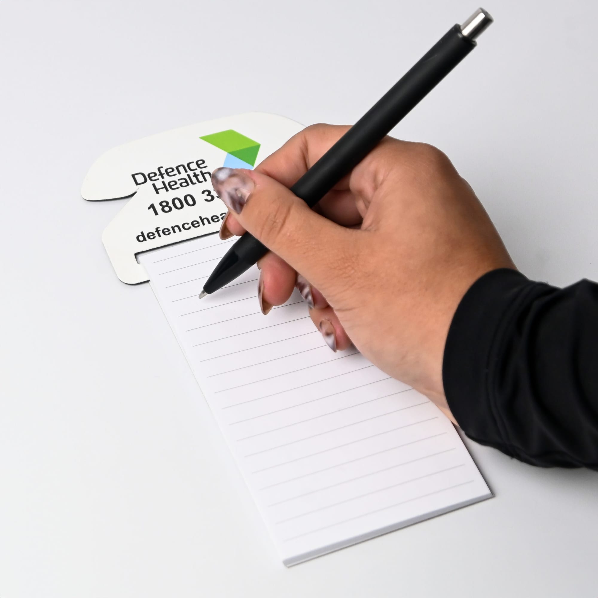 A house-shaped magnetic to-do list in white with a hand holding a black pen. It features a logo in the corner.