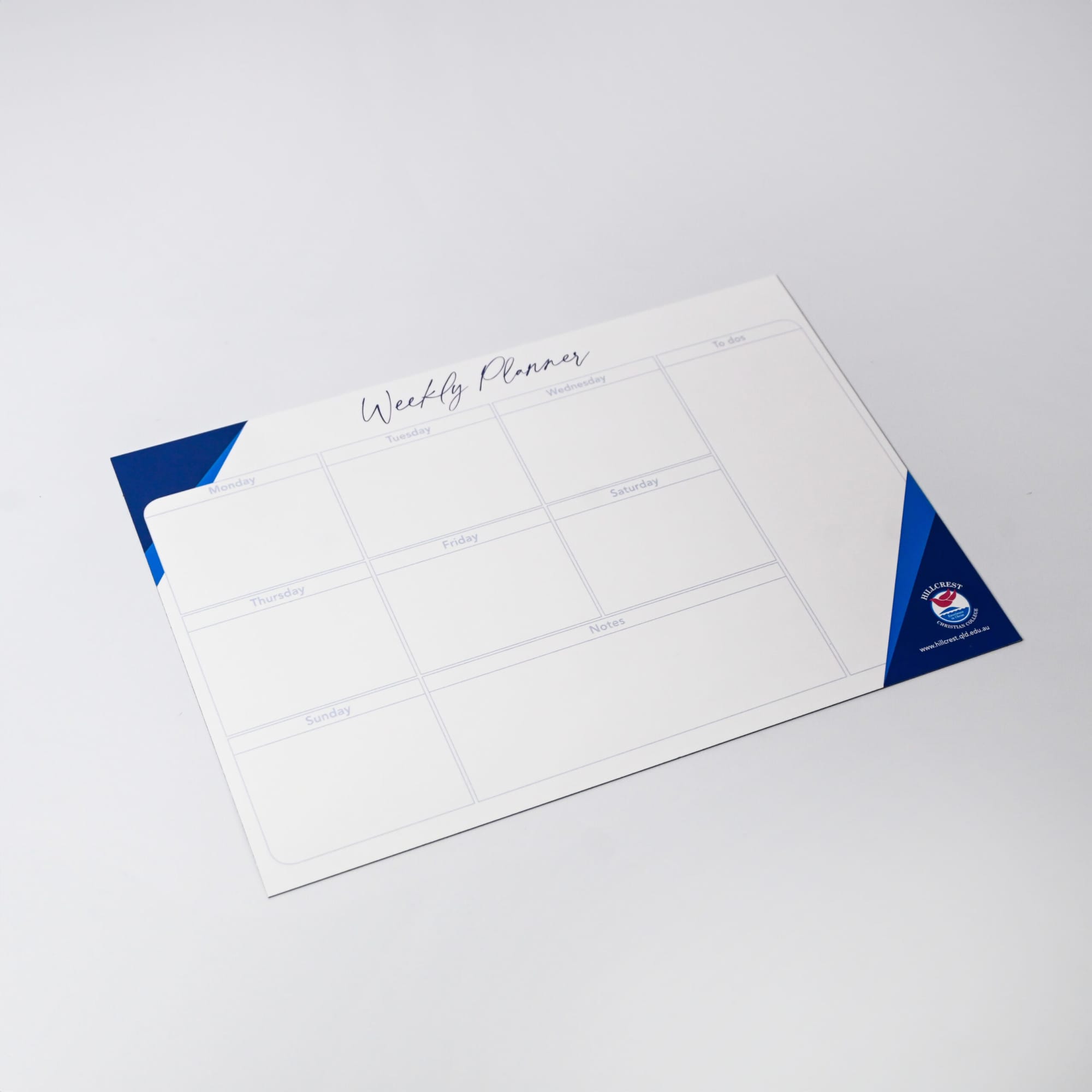 A magnetic whiteboard in white and blue, featuring a weekly planner layout with multiple sections.