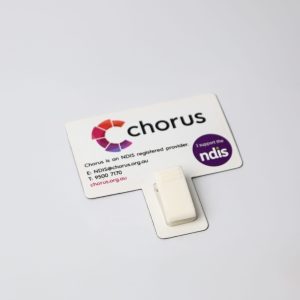 A white T-Magnet with a clip, attached to a printed card featuring logos and contact details.