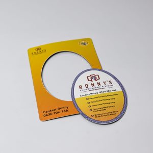 A magnetic photo frame in yellow with a circular cut-out, featuring a round promotional card with contact details.