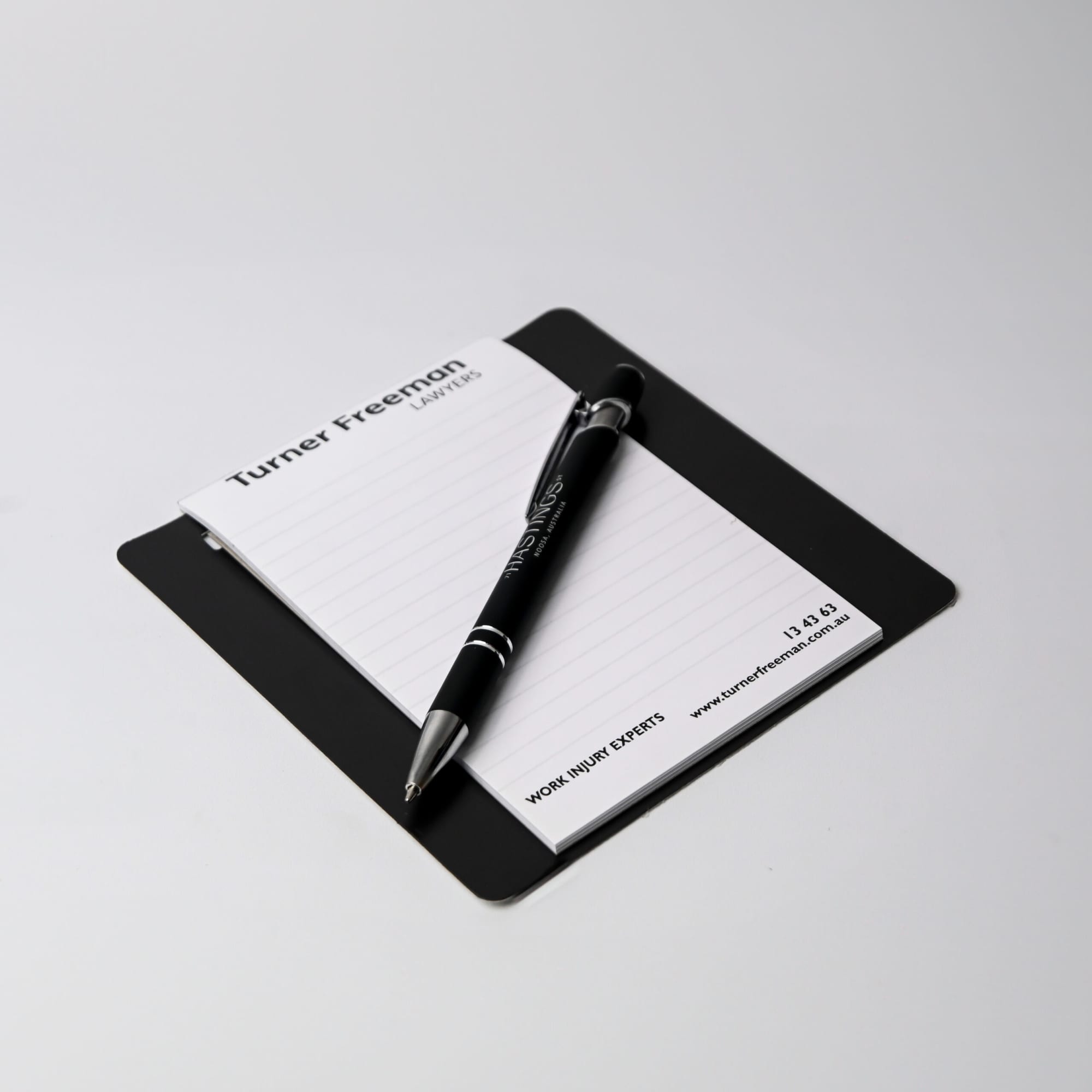 A white magnetic board with a notepad and a black marker, featuring a logo at the top.