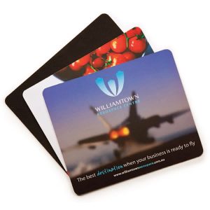 Three mouse mats featuring colourful designs, including images of tomatoes and an aircraft. One has a logo and branding.