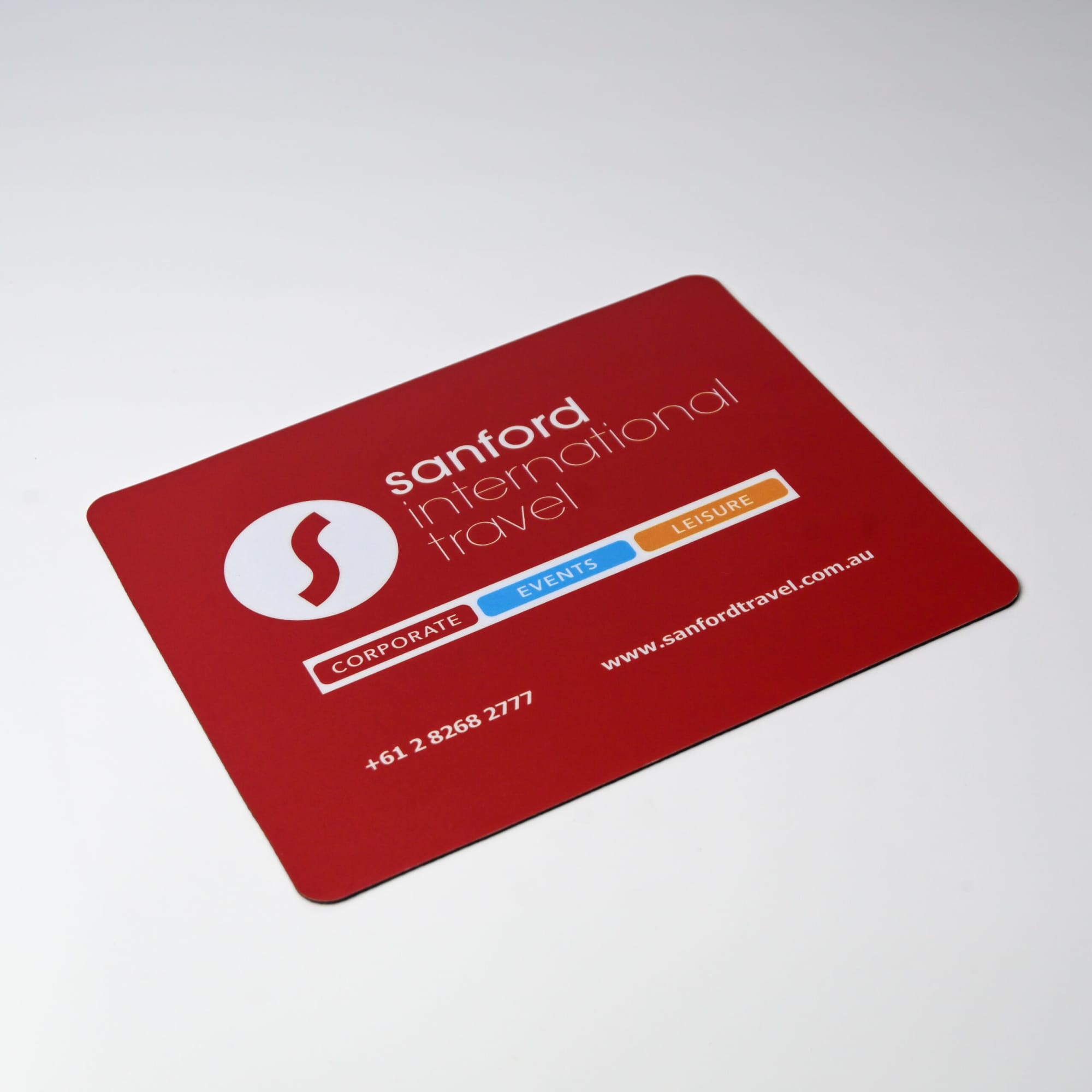 A red mouse mat featuring a logo, with contact details and categories for corporate, events, and leisure services.