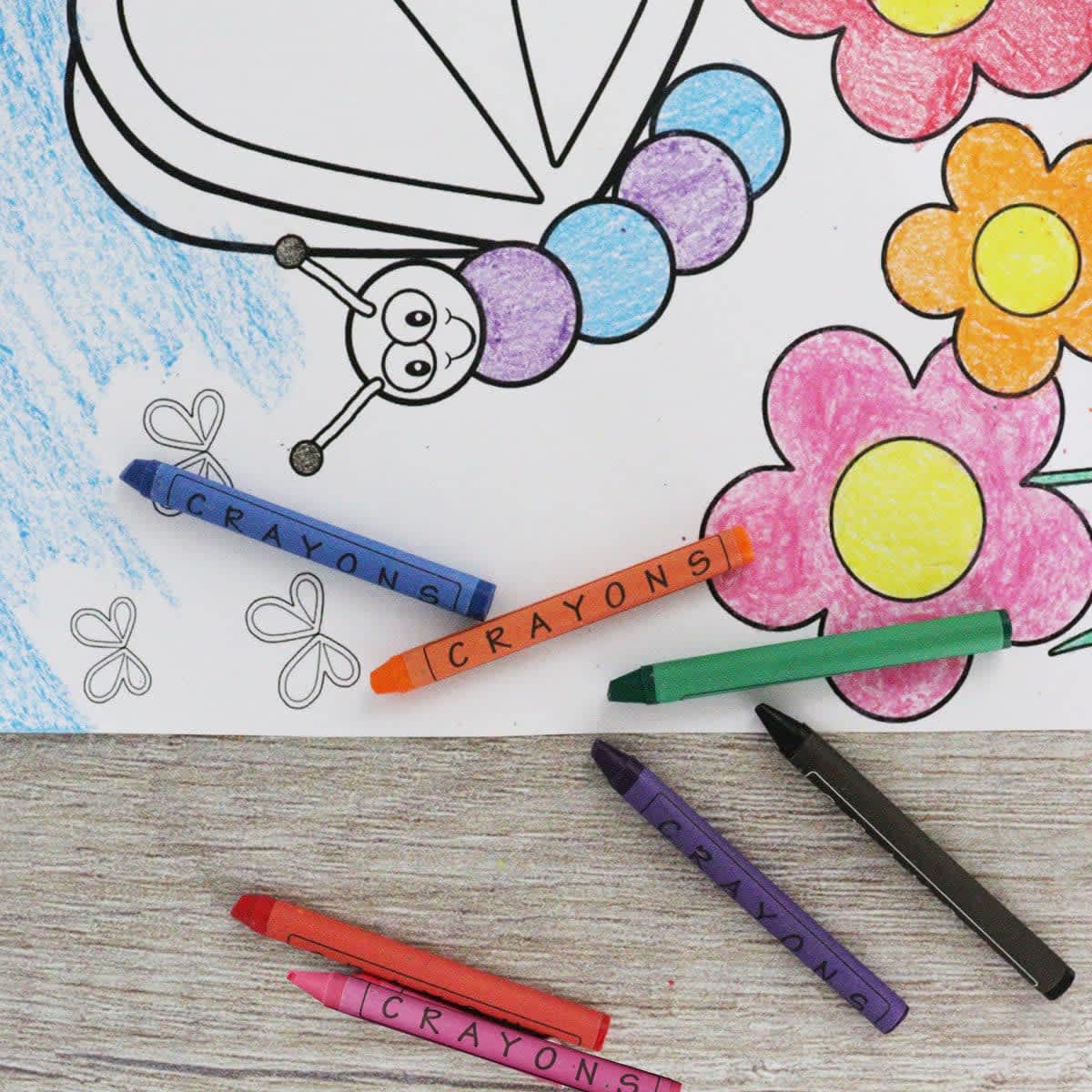 A set of colourful crayons in shades of purple, orange, green, red, and black on a colouring page with a butterfly and flowers.