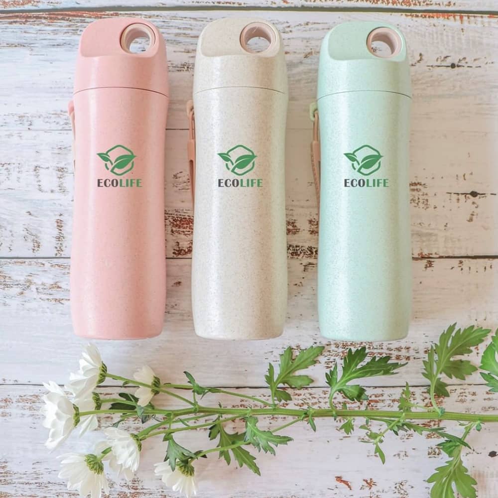 A drink bottle featuring three colours: pink, beige, and green, made from wheat straw, with a logo displayed.