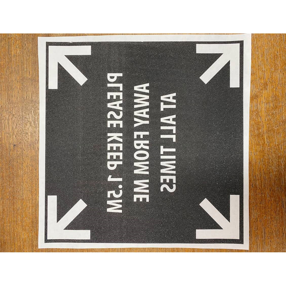 A square digital iron-on transfer with a black background and white text, featuring directional arrows and a logo.