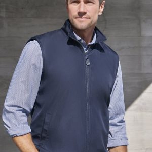 A man wearing a navy blue unisex reversible fleece vest, standing against a concrete background. The vest has a zip and a collar.