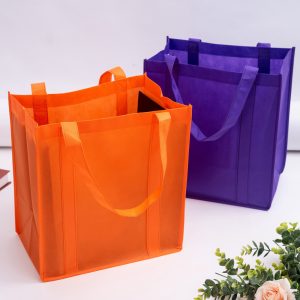 Two reusable shopping bags in vibrant orange and purple, featuring sturdy handles and a structured design.
