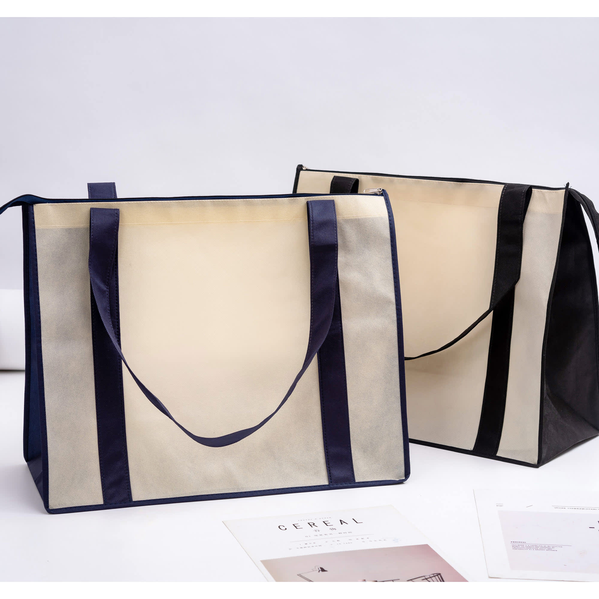 Two large zipped shopping bags in beige and black, featuring handles and a branding logo.