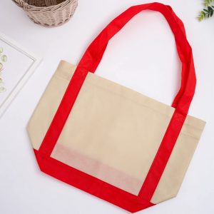 A large non-woven shopper bag in beige with red handles and accents. Features one logo on the front.
