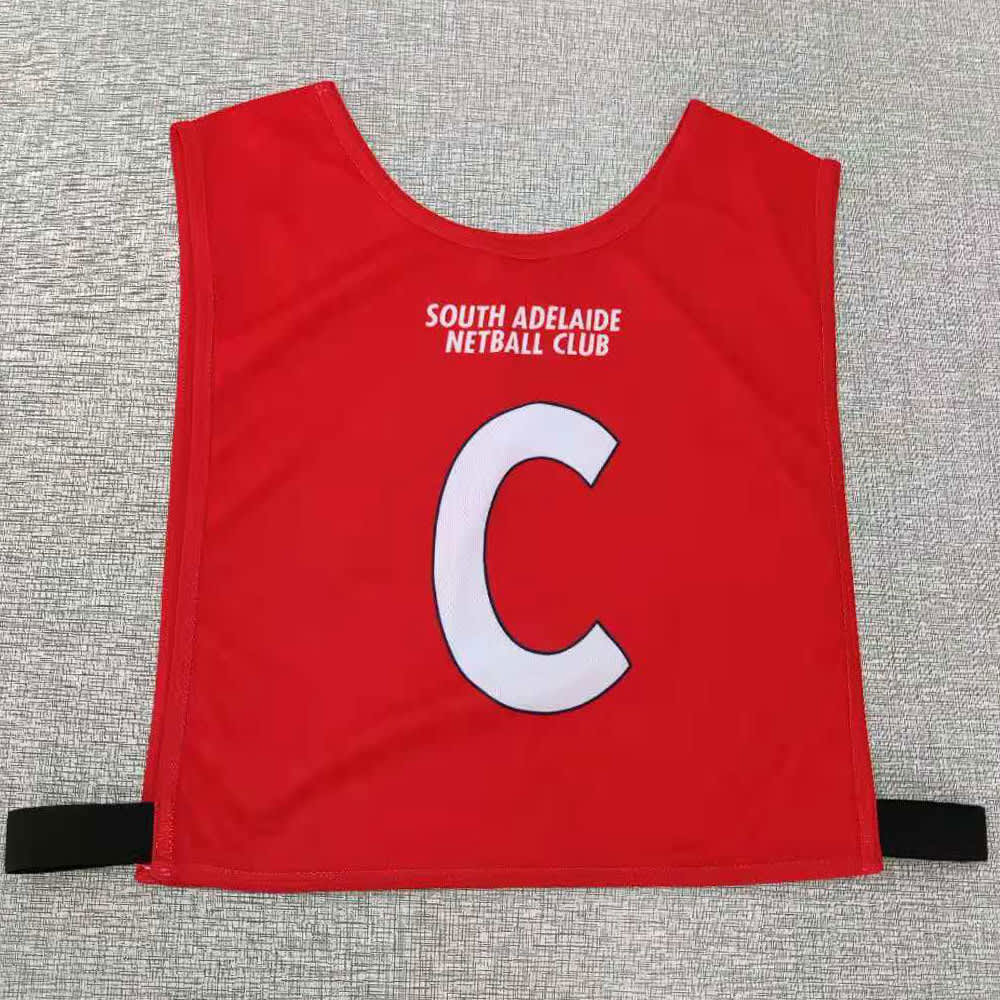 Red elastic netball bib featuring a large white 'C' and a logo from South Adelaide Netball Club.
