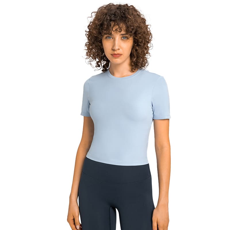 A light blue short sleeve top with a fitted design, paired with dark leggings, featuring a subtle logo.